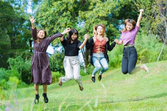 芝生でジャンプして喜ぶ学生たち