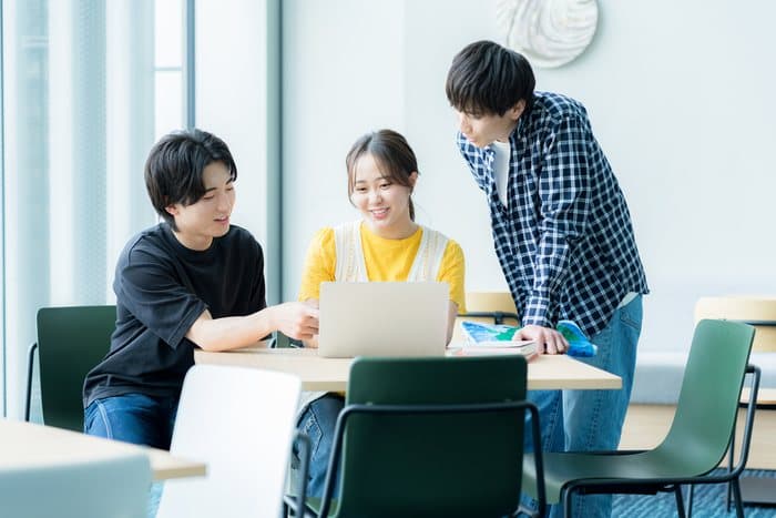 教室でノートPCを見ながら話し合う学生