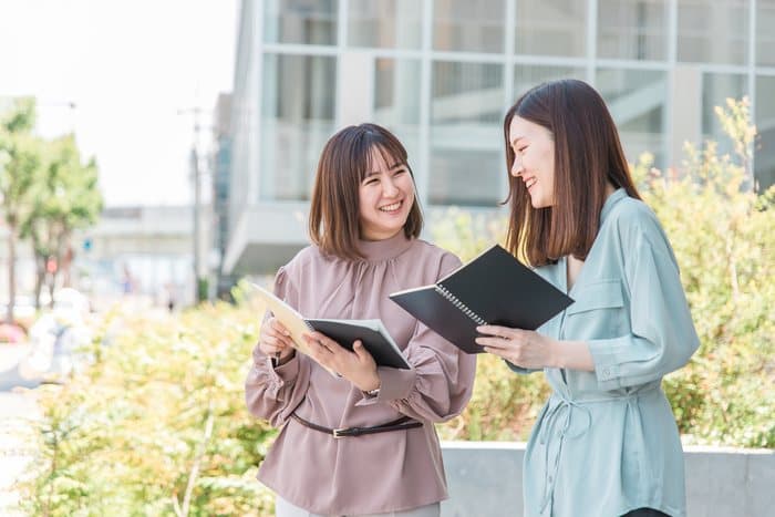 屋外でタブレットを見せ合う学生