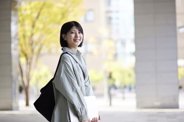 資料を抱えて笑顔で歩く学生